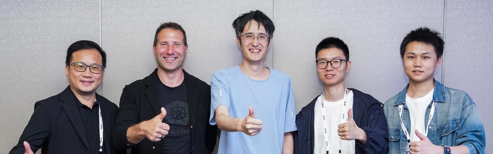 Five conference attendees standing together, smiling and giving thumbs up.