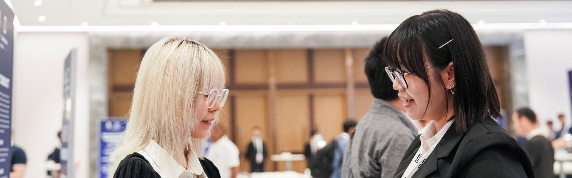 Two attendees talking at a conference networking area.
