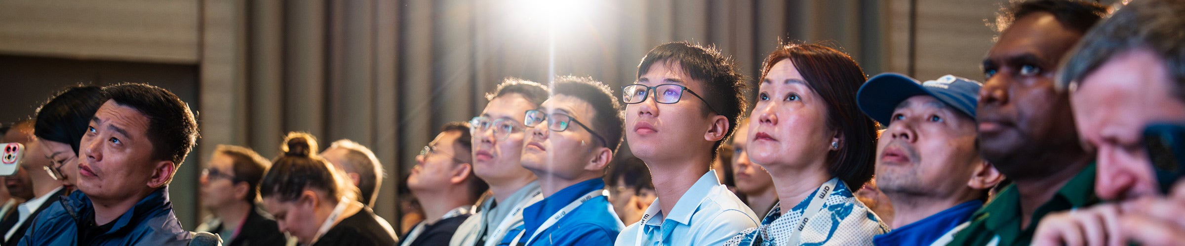 Conference attendees seated and watching a presentation attentively.