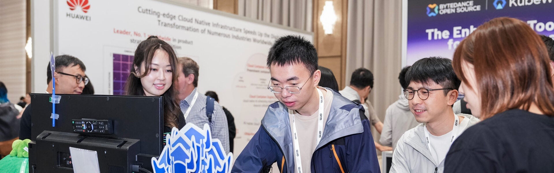 Attendees gathered around a demo screen at a conference exhibition booth.
