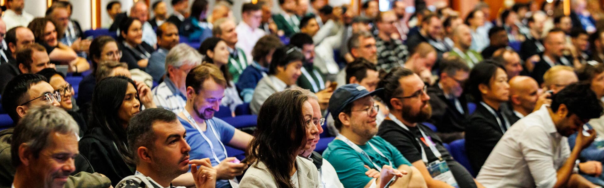 Large audience seated in a conference hall, attentively listening to a speaker during a presentation