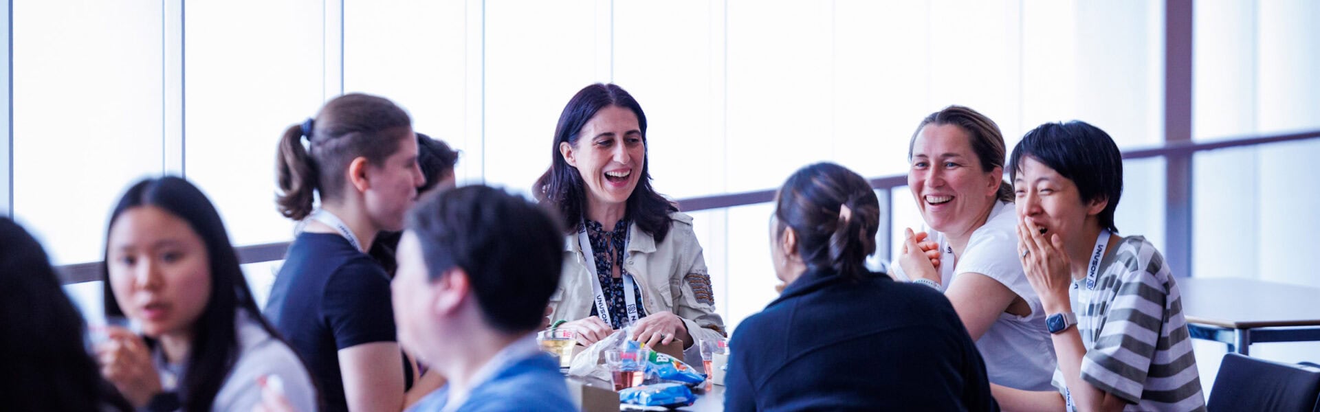 Group of attendees sitting together, smiling and talking while sharing snacks at a casual networking table